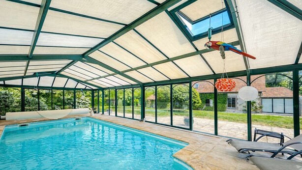 An indoor swimming pool with a glass ceiling, a parrot, and a hanging lantern. - La maison des tilleuls with swimming pool for 8 people (Saint-Sulpice-sur-Risle)