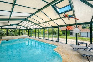 An indoor swimming pool with a glass ceiling, a parrot, and a hanging lantern.