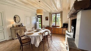 A dining area with a round table, chairs, and a fireplace. - La maison des tilleuls with swimming pool for 8 people (Saint-Sulpice-sur-Risle)