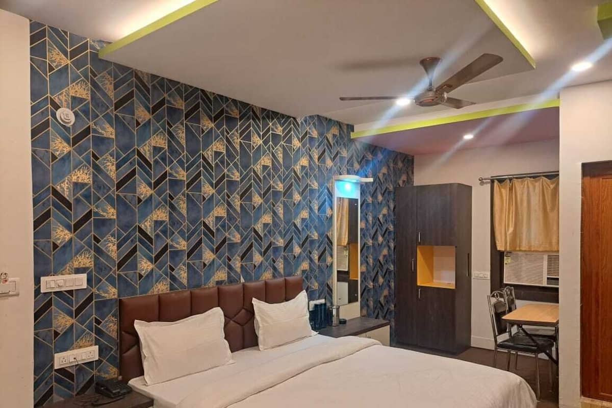 A hotel room with a bed, a desk, a chair, a wardrobe, and a ceiling fan.