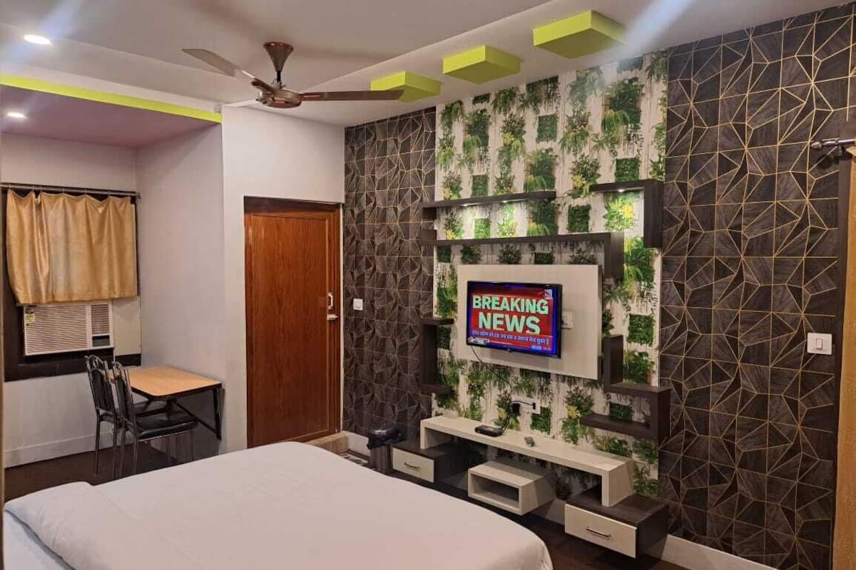 A modern hotel room with a bed, a desk, and a TV mounted on the wall.