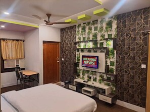 A modern hotel room with a bed, a desk, and a TV mounted on the wall. - Hotel Coastal Bay (Bhubaneshwar)