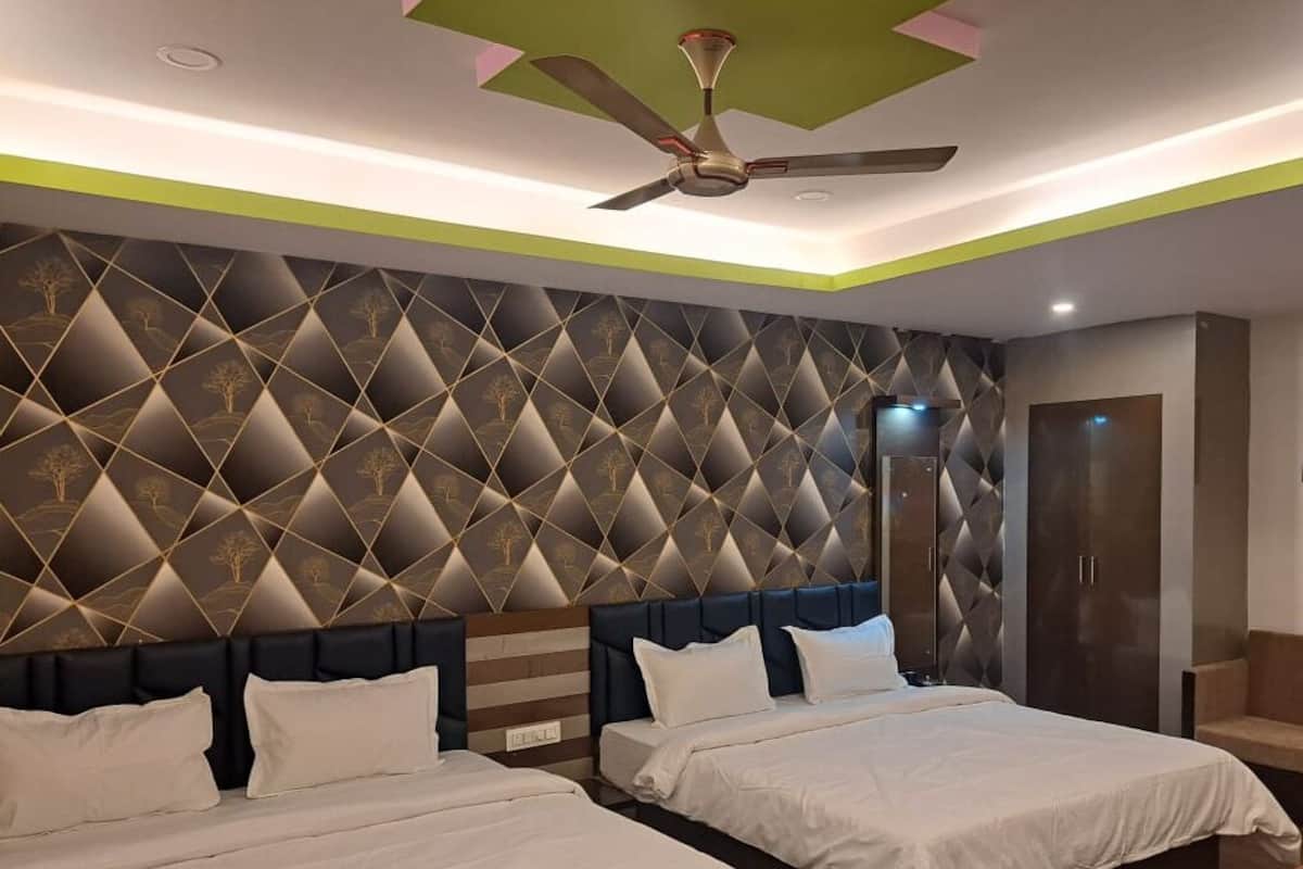 A modern hotel room with two beds, a ceiling fan, and a geometric patterned wall.