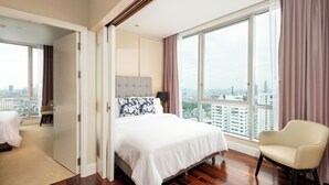 A modern hotel room with a large bed, a chair, and a city view through large windows. - Serviced 2 Bed Superior Skyvillas - Check in From 15h to 22h Only (Bangkok)