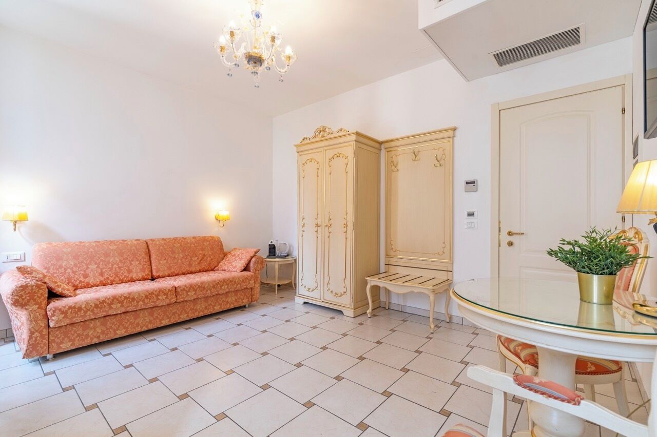 Un salon comprenant un canapé, un meuble, une table ronde avec des chaises et un lustre.