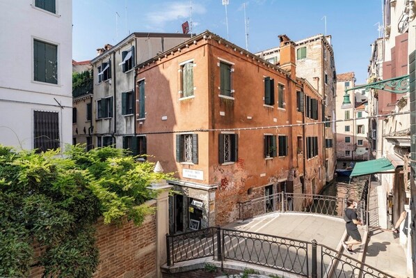 A narrow street with buildings on either side, a small bridge, and a person walking. - Casa Marsilli (Venice)