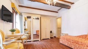 A bedroom with a bed, a TV, a wardrobe, and a small table with a plant. - Casa Marsilli (Venice)