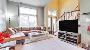A living room with a sectional sofa, a coffee table, a TV on a stand, a staircase, and a glass display cabinet. - Family-Friendly Home w/ Patio & Garden in Everett! (Everett)