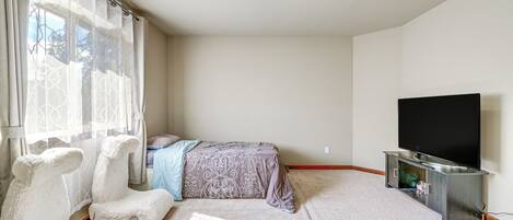 A bedroom with a bed, a TV, and a window with curtains.