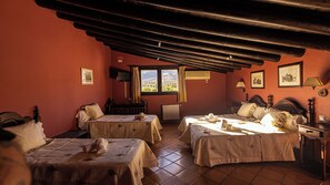 A cozy room with two beds, a window with curtains, a radiator, and framed pictures on the walls. - Hotel La Casa Grande del Burgo (El Burgo)