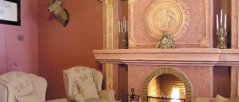 Una sala de estar acogedora con chimenea, dos sillones, un sofá y una cabeza de venado decorando la pared.