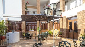 An outdoor patio area with tables and chairs, surrounded by brick walls and potted plants. - Hotel La Casa Grande del Burgo (El Burgo)