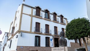 A white building with multiple balconies and a statue in front. - Hotel La Casa Grande del Burgo (El Burgo)