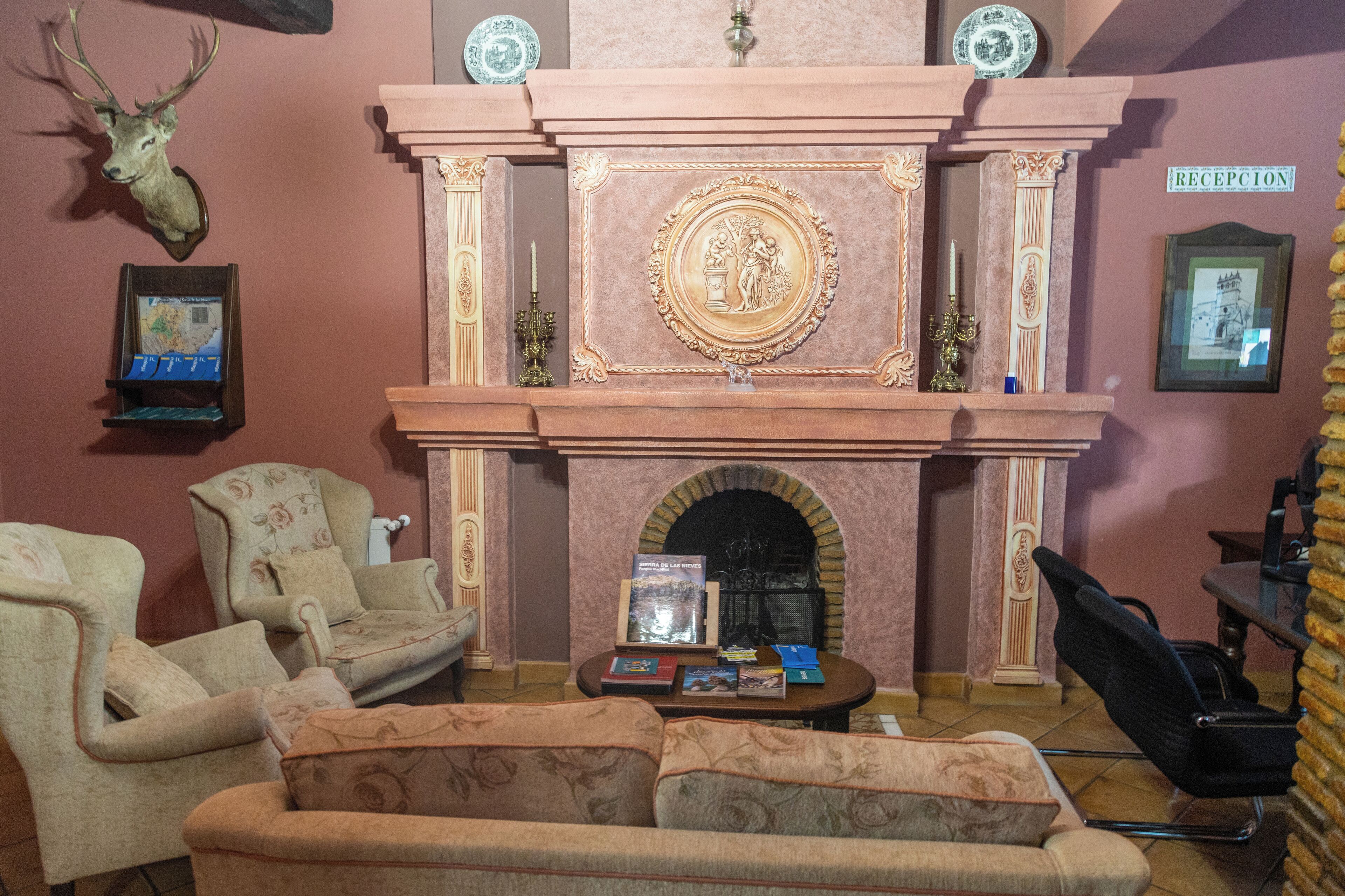 Een gezellige woonkamer met een open haard, twee fauteuils, een bank en een salontafel.