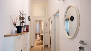 Ein Hotelkorridor mit Holzboden, weißen Wänden, einem Spiegel und einem Regal mit Dekoration.