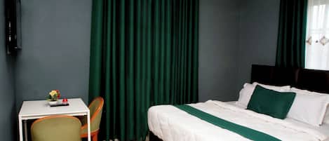 A hotel room with a bed, a desk, and a chair.