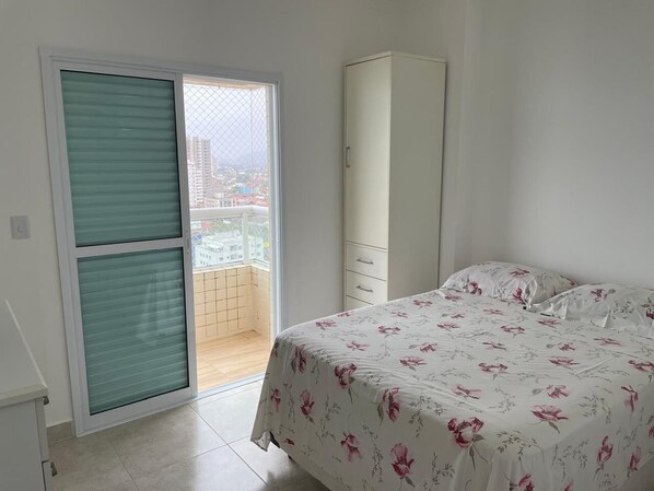 A bedroom with a bed, a wardrobe, and a sliding glass door leading to a balcony.