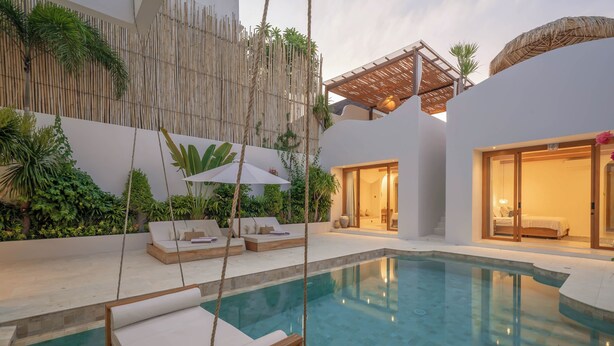 A modern pool area with lounge chairs, a bamboo wall, and a well-lit interior. - Villa Milana (Canggu)