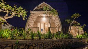 A wooden structure with a pitched roof, surrounded by lush greenery and a stone wall. - Wijaya Cottage Nusa Penida (Penida Island)