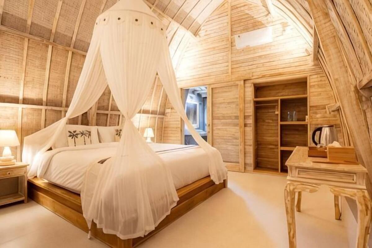 A bedroom with a canopy bed, wooden walls, and a small table with a lamp.