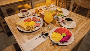 A breakfast table with plates of food, a glass of orange juice, and a cup of coffee. - Wijaya Cottage Nusa Penida (Penida Island)