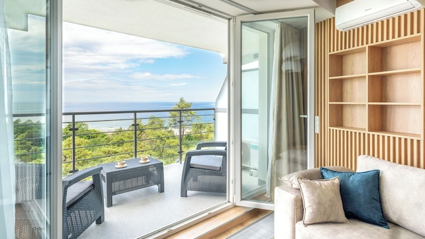 A balcony with wicker furniture, a sofa, and a view of the sea.