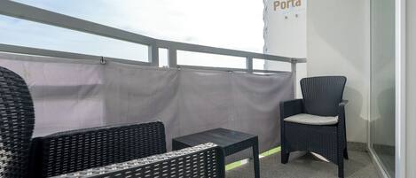 A balcony with wicker furniture, a grey curtain, and a wall with 'Porta Wellness' signage.
