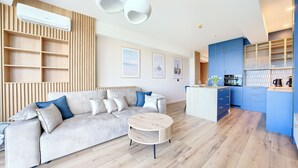 A modern living room with a sofa, a coffee table, and a kitchen area with blue cabinets.