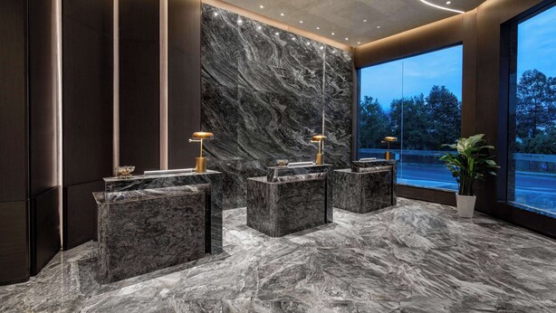 A modern lobby with marble reception desks, a large marble wall, and a view of the outdoors. - Days Hotel by Wyndham Renhuai Canglong (Zunyi)