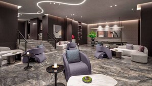 A modern lobby with a marble floor, grey sofas, and a staircase leading to upper floors. - Days Hotel by Wyndham Renhuai Canglong (Zunyi)