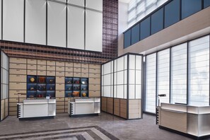 A modern reception area with a central desk, a display of trophies, and a large window providing natural light.