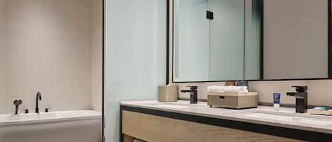 A modern bathroom with a freestanding bathtub, a large mirror, and a wooden vanity with a countertop.