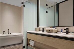 A modern bathroom with a freestanding bathtub, a large mirror, and a wooden vanity with a countertop.