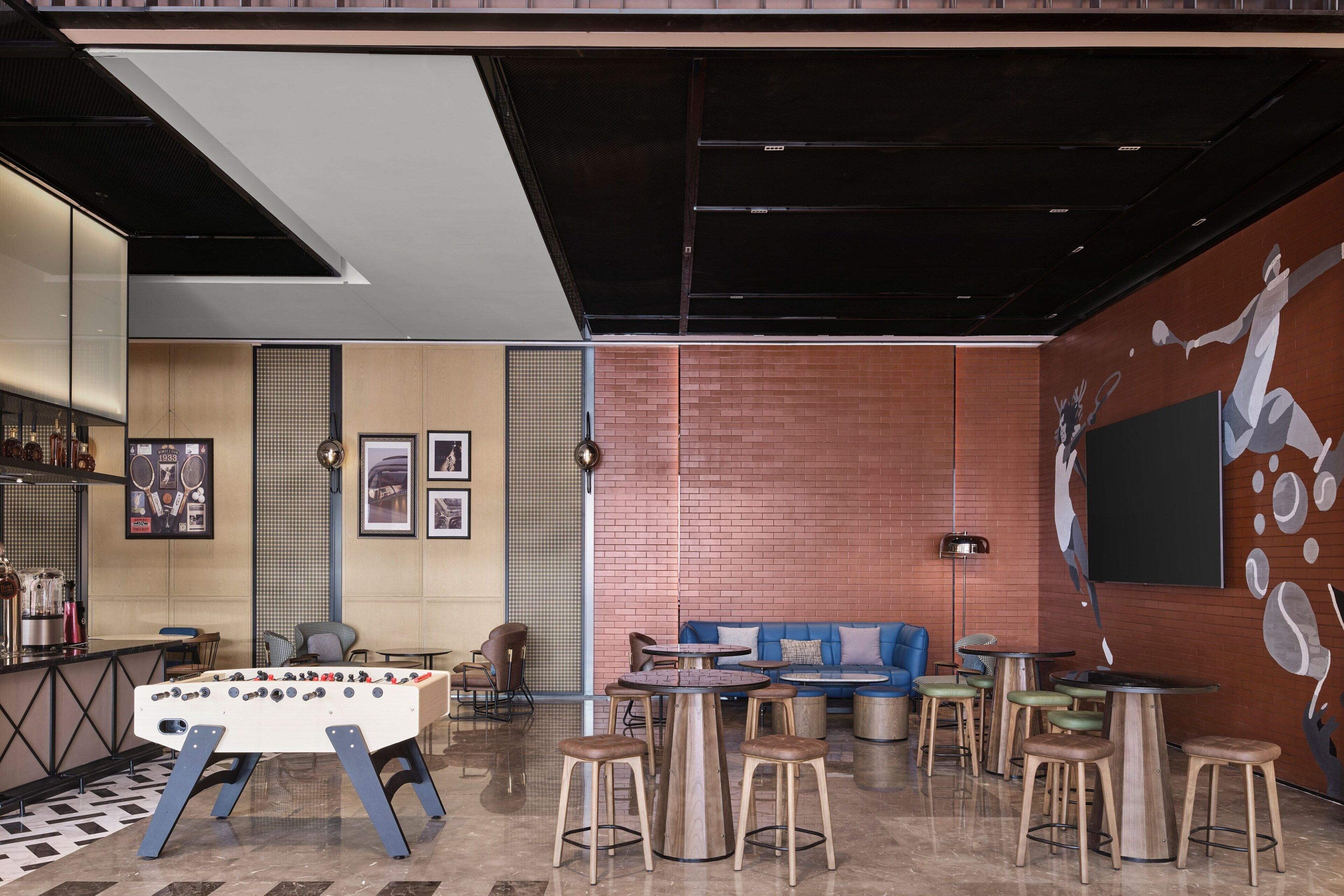 Een moderne lounge met een tafelvoetbalspel, zitplaatsen en een muurschildering.