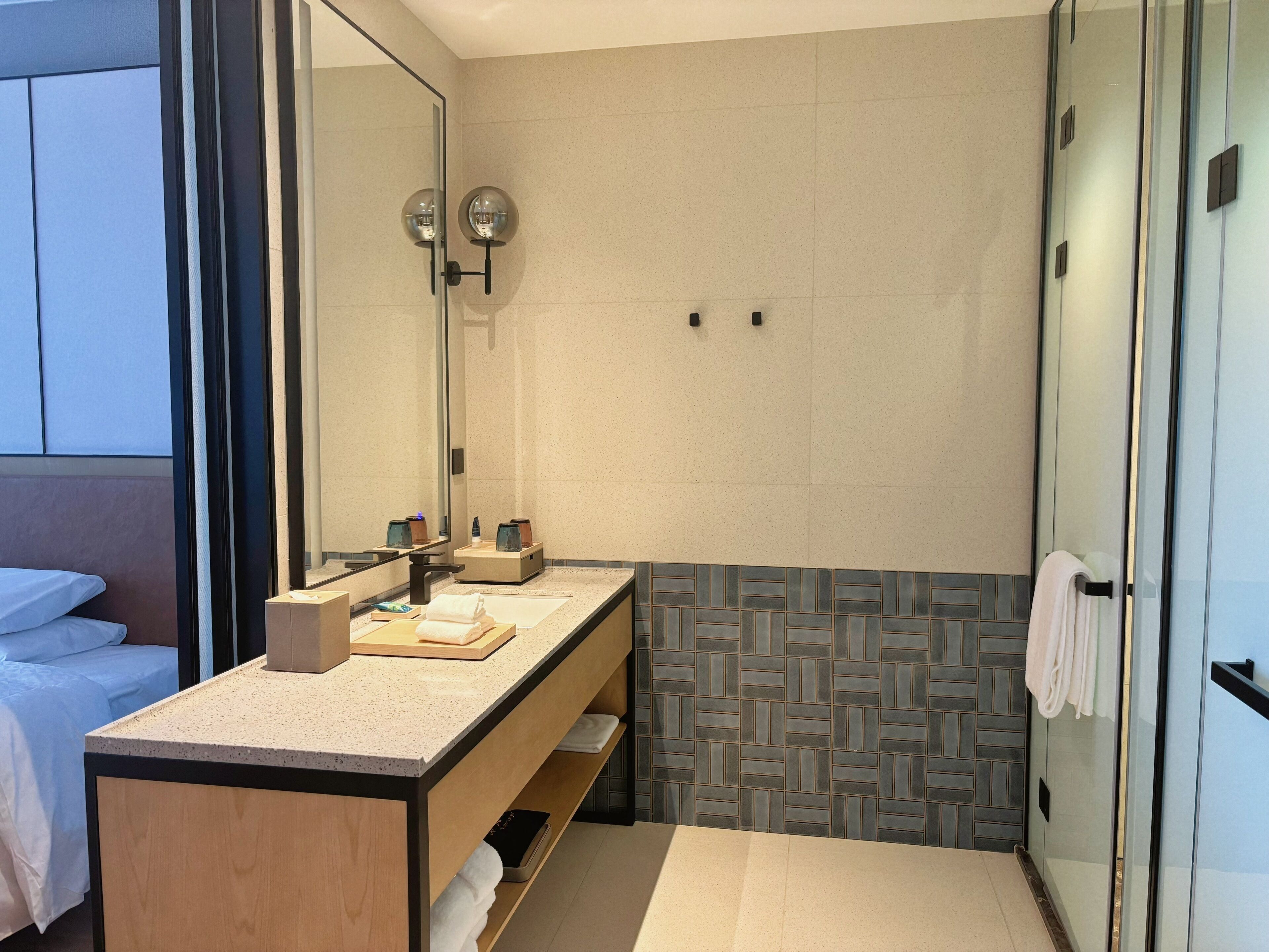 Un baño moderno con tocador doble, un espejo grande y zona de ducha con puerta de cristal.