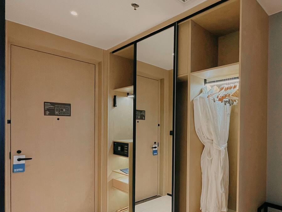 A hotel room with a large mirror, a wardrobe, and a small desk with a computer.