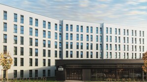 Ein modernes Gebäude mit symmetrischer Fassade, zahlreichen Fenstern und einem markanten Eingang mit Glasüren.
