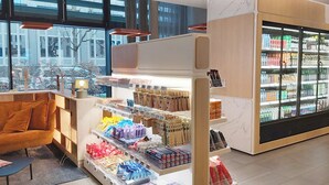 Ein moderner Verkaufsbereich mit Regalen voller verschiedener Produkte, einer Sitzecke mit einer Couch und einem Kühlvitrine.