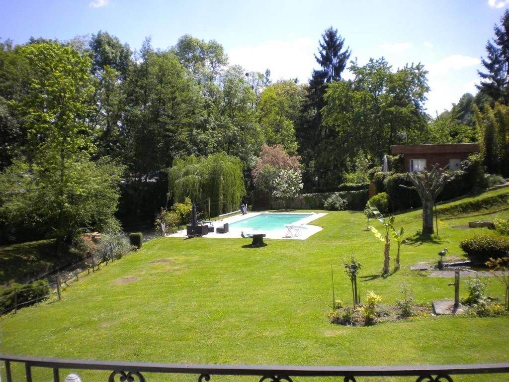 A well-maintained garden with a swimming pool, surrounded by lush greenery and trees.