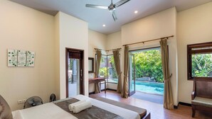A hotel room with a bed, a desk, a chair, and a view of a swimming pool. - Senang Villa by Betterplace (Canggu)