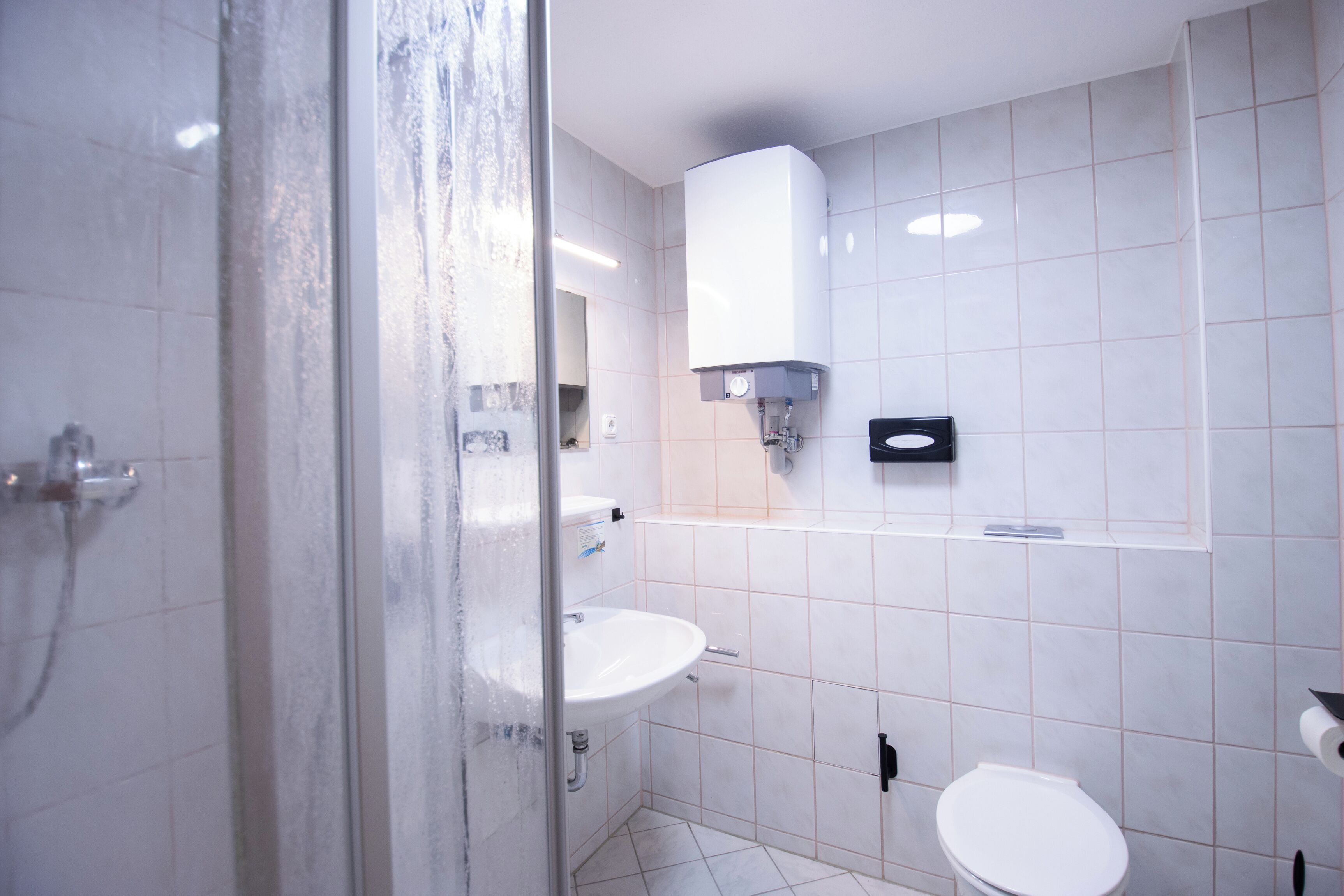 A modern bathroom with a glass shower enclosure, a white sink, and a toilet.