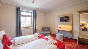 Ein Hotelzimmer mit zwei Betten, einem Fernseher, einem Schreibtisch und einem Sessel.