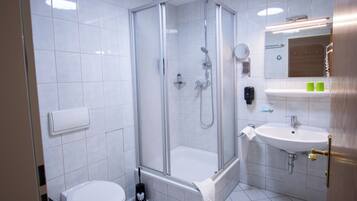 A modern bathroom with a glass-enclosed shower, a white sink, and a toilet.