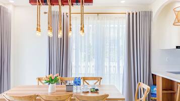 A dining area with a wooden table and chairs, a vase with flowers, and bottles of water.