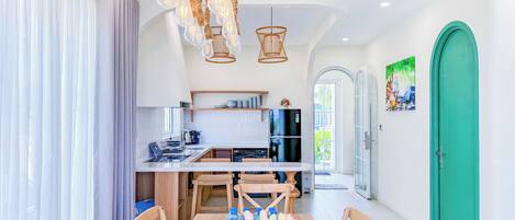 A modern kitchen with a built-in oven, a dining area with a wooden table and chairs, and a green door.
