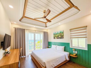Une chambre à coucher comprenant un lit, un bureau, un ventilateur de plafond, une fenêtre avec des stores et une vue sur l’extérieur.
