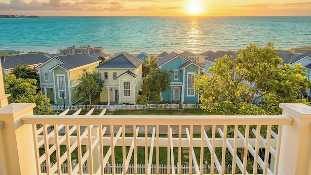 A coastal residential area with houses and a view of the ocean during sunset.