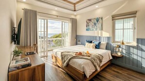 A bedroom with a bed, bedside table, and a view of the outdoors. - Novaworld Phan Thiet - Alala Stay (Tien Thanh)