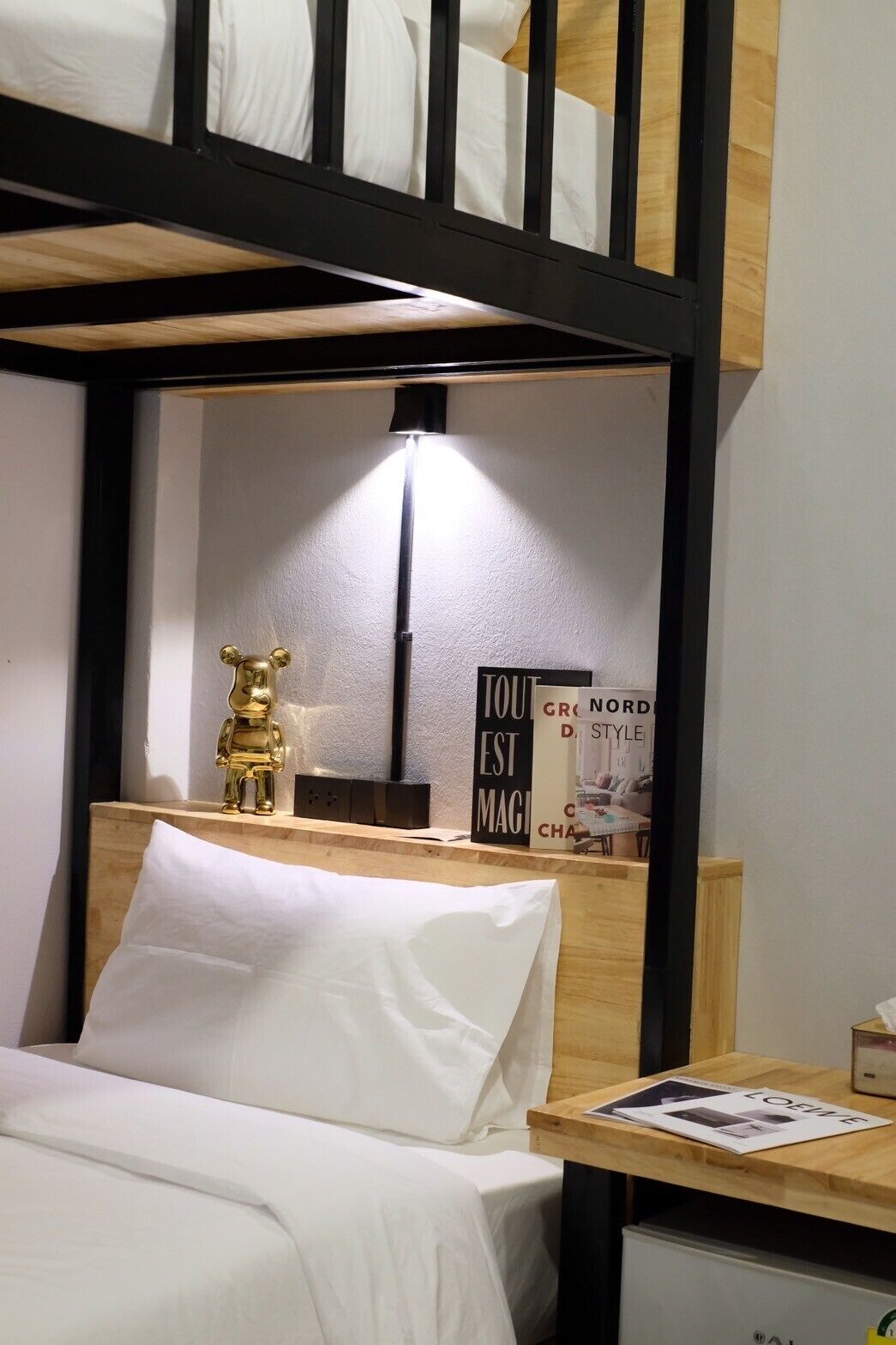 Ein Etagenbett mit Nachttisch, Lampe, einer kleinen goldenen Figur und einem Schild mit Text.