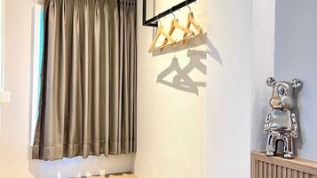 Quarto de canto com janela, um banco de madeira, um radiador e um cabide fixado na parede.